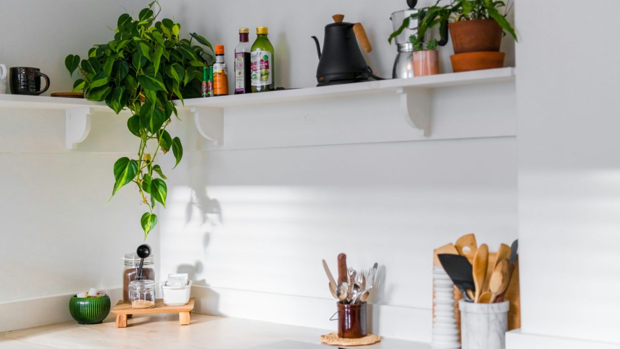 organized small kitchen with labeled storage boxes, hanging racks, and countertop decor — DIY tips to make life easier at home